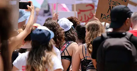 Várias pessoas com cartazes em passeata lutando pelos direitos humanos.